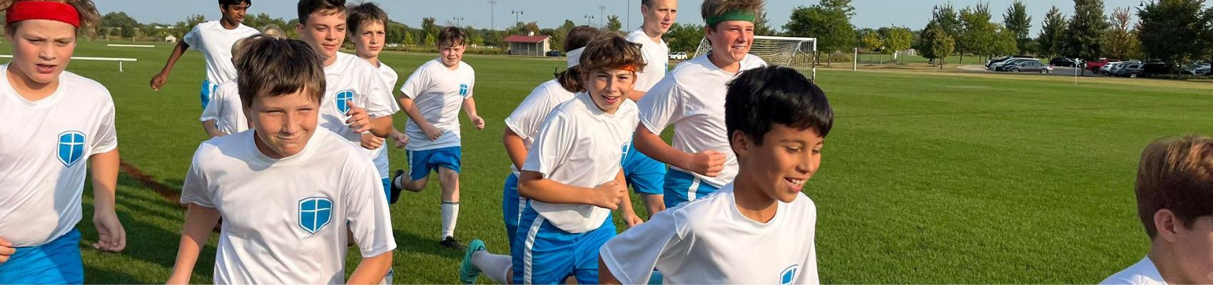 Middle School boys running and smiling in soccer uniforms